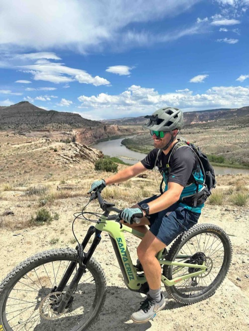 Taylor Dickey, DO, on his mountain bike above a river canyon